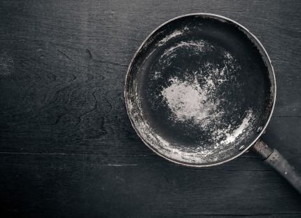 Vanha ja kulunut paistinpannu tumman pinnan päällä.