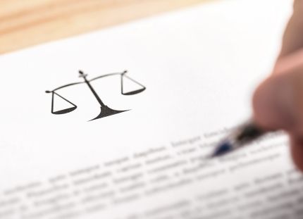 Tuntematon hahmo lukee lakitekstiä kynä kädessä.