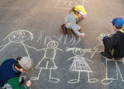 Täysin rokottamattomien lasten osuus on kasvussa. Lapset leikkivät kadulla ja piirtävät katuliiduilla asfalttiin ihmishahmoja.