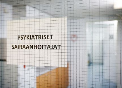 Kuva sairaalan käytävästä, jossa kiinni oleva lasiovi ja siinä tulostettu lappu tekstillä "psykiatriset sairaanhoitajat".