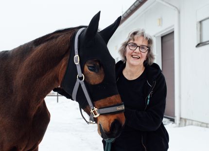 Kirsi Nicklén seisoo hevosen vierellä ulkona.