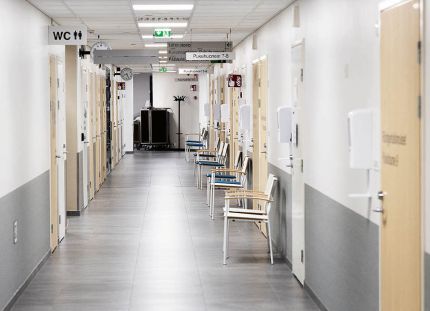 Kuvituskuva sairaalan käytävästä. Tyhjällä käytävällä muutamia tuoleja.