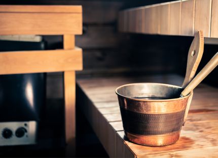 Saunan laiteilla löylykaukalo. Taustalla näkyy kiuas.