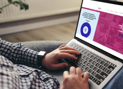 Soste irtisanoo lähes puolet työntekijöistään. Mies selaa kannettavalla tietokoneella Sosten verkkosivuja.