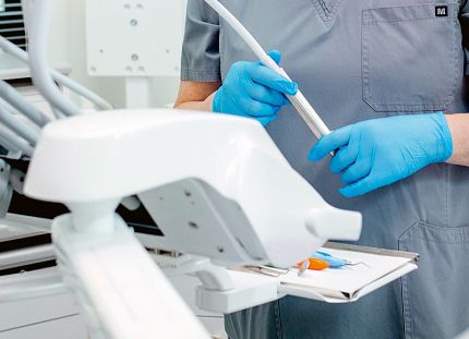 Suuhygienisti työvälineidensä äärellä suojahansikkaat kädessä.