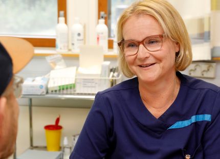 Heidi Salmenoja työpöydän takana, toisella puolella potilas.