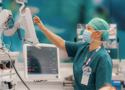 Hoitaja käy läpi leikkaussalin laitteita.