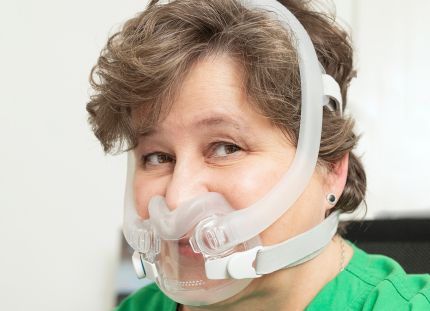 Nainen, jolla on CPAP-maski kasvoillaan. 