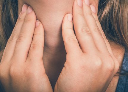 Nainen pitelee kaulaansa.