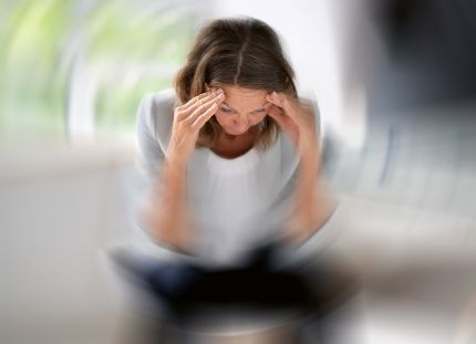 Nainen pitelee päätään.