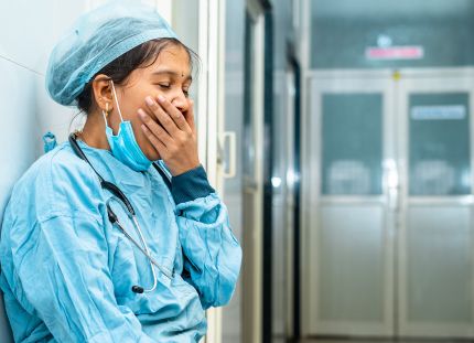 Lattialla istuva hoitaja haukottelee.