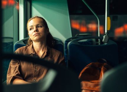 Väsynyt nainen katsoo ikkunasta ulos linja-autossa. Työssä jaksamisen ongelmat yhdistävät julkista ja yksityistä sote-alaa.