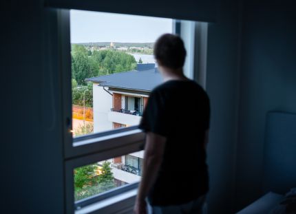 Työttömyys heikentää merkittävästi etenkin työikäisten miesten mielenterveyttä. Ihmishahmo seisoo ikkunan edessä selin kameraan tummassa huoneessa.