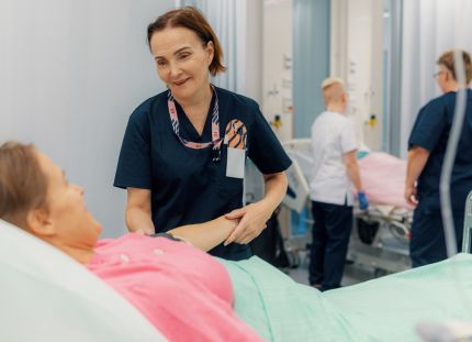 Keski-ikäinen hoitaja työssään sairaalassa auttaa potilasta – hyvät työolot ja terveystottumukset tukevat ikääntyvien työntekijöiden työkykyä ja jaksamista.