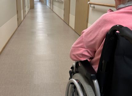 Vanhusasiavaltuutetun mukaan esimerkiksi ympärivuorokautisen hoidon ja kotihoidon kriteerejä on tiukennettu kohtuuttomasti. Vanhus ymoärivuorokautisessa hoidossa pyörätuolissa käytävällä.