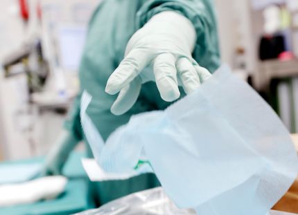 Käsi, jossa hansikas heittää roskan roskikseen.