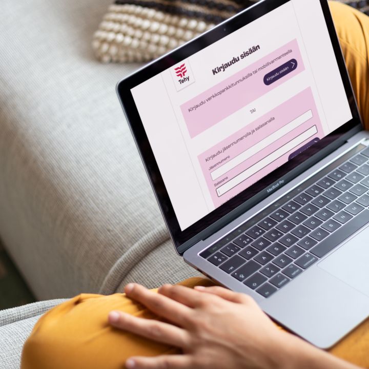 Nainen istuu sohvalla ja katsoo läppäriltä asiointipalvelua