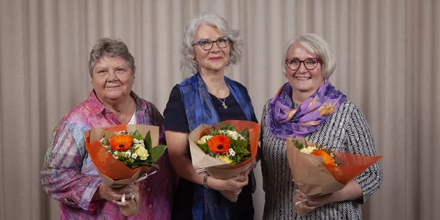 Kolme naista kukkakimppujen kanssa