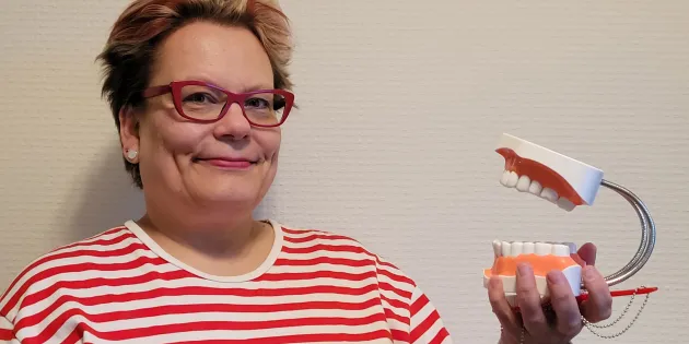 Nainen pitää hammashallia kädessään.