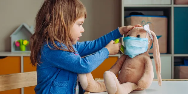 Pikkutyttö leikkii lääkäriä ja antaa rokotteen pehmolelu jänikselle.
