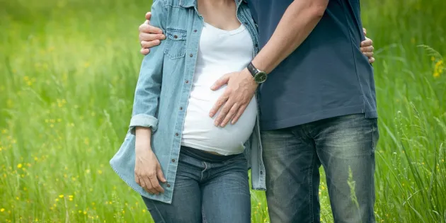 Raskaana oleva nainen niityllä miehen kanssa.