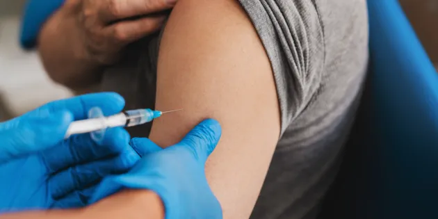 Hoitaja antaa henkilölle rokotteen käsivarteen.