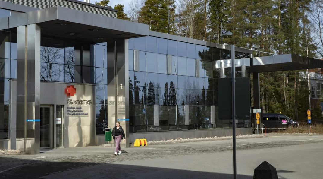 Sairaalan pihalla kävelee ihminen.