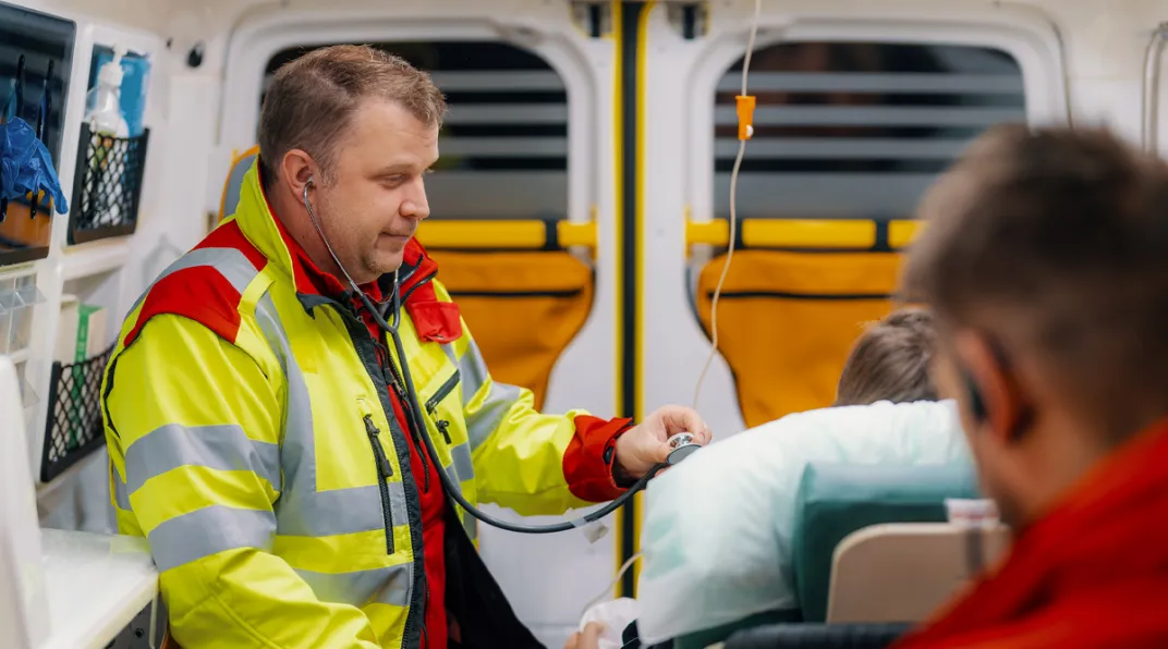 Kaksi ensihoitajaa hoitaa potilasta ambulanssissa.