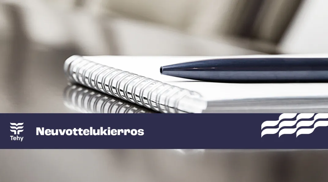 Neuvottelupöytä, jossa lehtiö ja kynä. Sininen nauha, jossa teksti "neuvottelukierros".