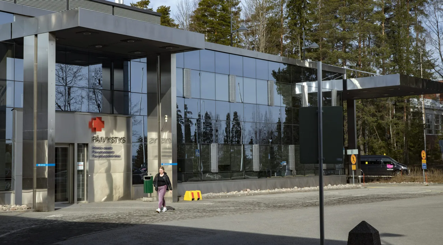 Sairaalan pihalla kävelee ihminen.