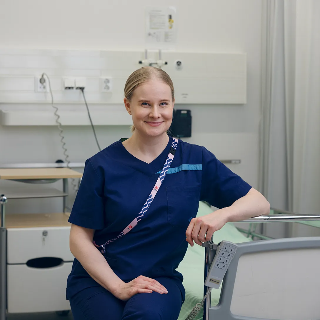 Hoitaja istuu sairaalasängyllä