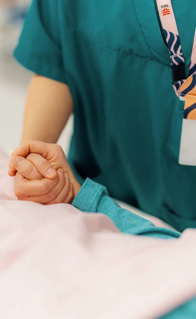 Hoitaja pitää potilaan kättä