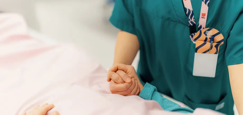 Hoitaja pitää potilaan kädestä kiinni