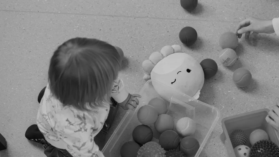 Lapsi leikkii lastenhoitajan kanssa lattialla