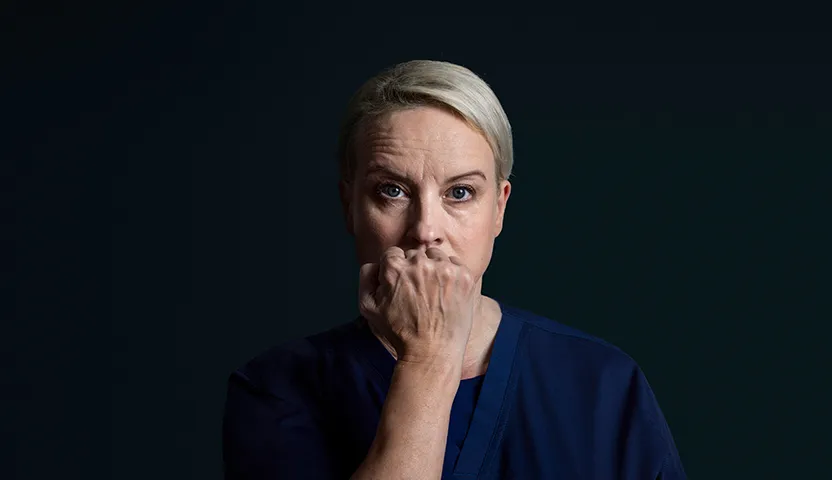 Hoitaja nyrkki suun edessä